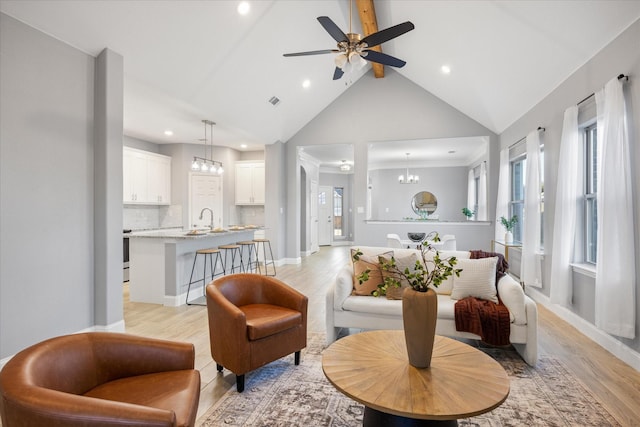 living room featuring light hardwood / wood-style floors, sink, lofted ceiling with beams, and ceiling fan with notable chandelier