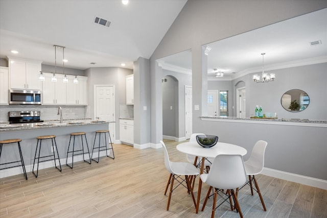 dining room with sink, crown molding, and lofted ceiling