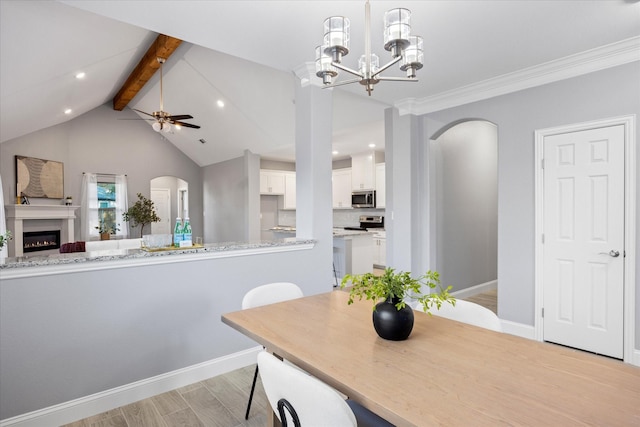 dining space featuring crown molding, light wood-type flooring, ceiling fan with notable chandelier, and vaulted ceiling with beams