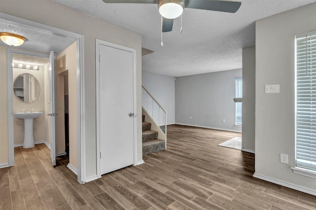 hallway with sink, wood-type flooring, a textured ceiling, and a healthy amount of sunlight