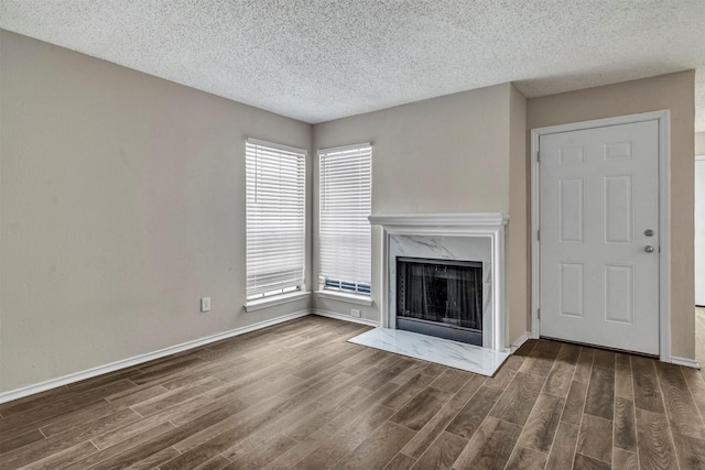 unfurnished living room with a textured ceiling, dark hardwood / wood-style floors, and a high end fireplace