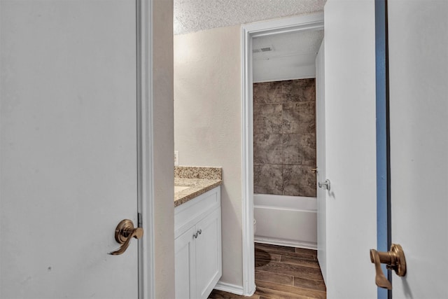 full bathroom featuring a textured ceiling, toilet, vanity, and shower / tub combination