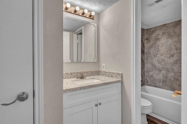 full bathroom with a textured ceiling, hardwood / wood-style floors, washtub / shower combination, vanity, and toilet