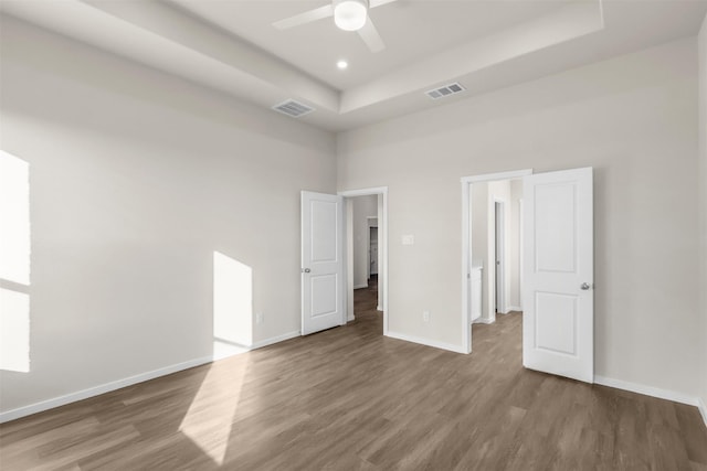 unfurnished bedroom featuring ceiling fan, dark hardwood / wood-style flooring, a raised ceiling, and a towering ceiling