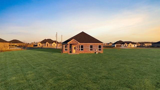 back house at dusk with a lawn