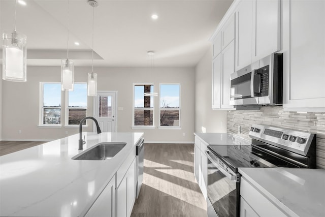 kitchen with appliances with stainless steel finishes, pendant lighting, white cabinetry, and sink