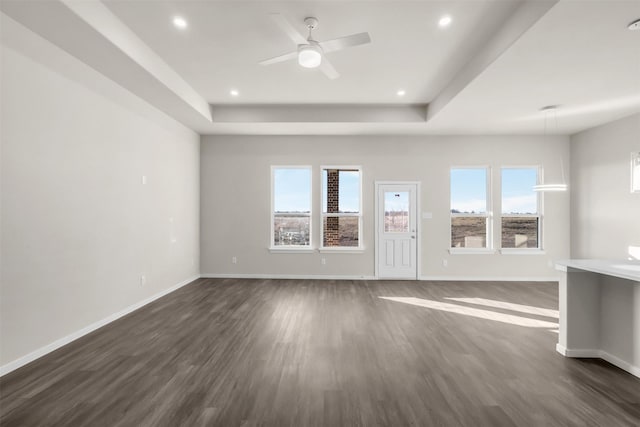 unfurnished living room with ceiling fan, dark hardwood / wood-style flooring, and a raised ceiling