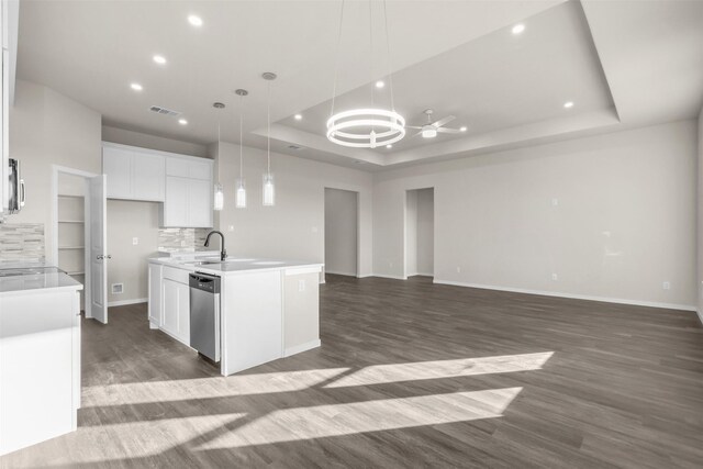 kitchen featuring white cabinetry, a center island with sink, a raised ceiling, dishwasher, and hanging light fixtures