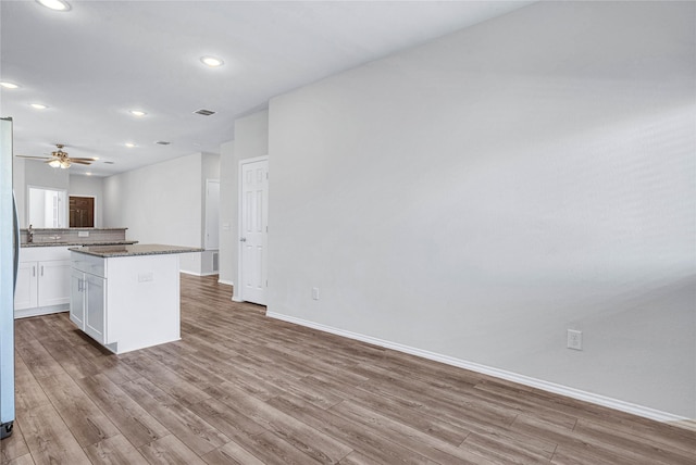 kitchen featuring white cabinets, dark stone counters, light hardwood / wood-style floors, and a center island