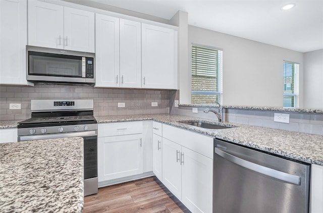 kitchen with light stone counters, sink, white cabinets, and stainless steel appliances