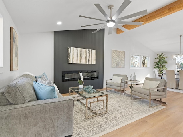 living room featuring vaulted ceiling with beams, wood-type flooring, and ceiling fan with notable chandelier