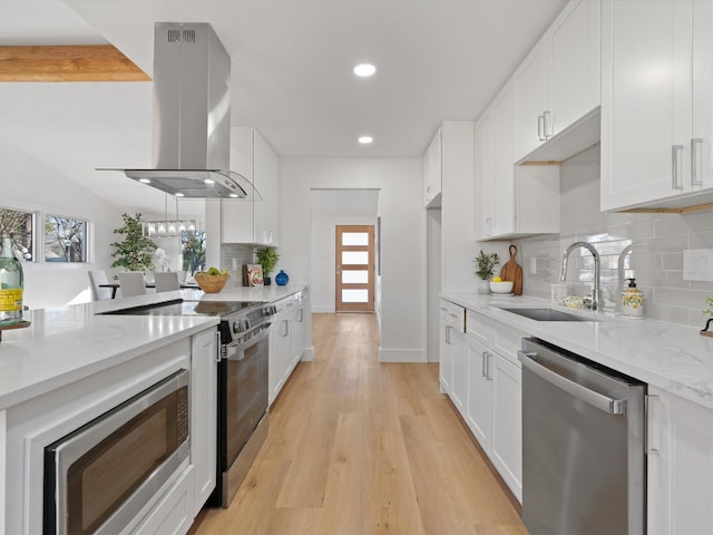 kitchen with tasteful backsplash, white cabinets, appliances with stainless steel finishes, and island range hood