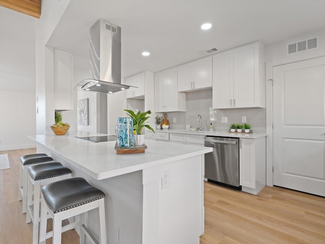 kitchen with kitchen peninsula, white cabinetry, island range hood, and dishwasher