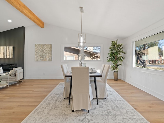 dining space with lofted ceiling with beams and light hardwood / wood-style flooring