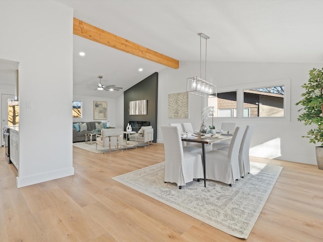 dining area featuring ceiling fan with notable chandelier, lofted ceiling with beams, and light wood-type flooring