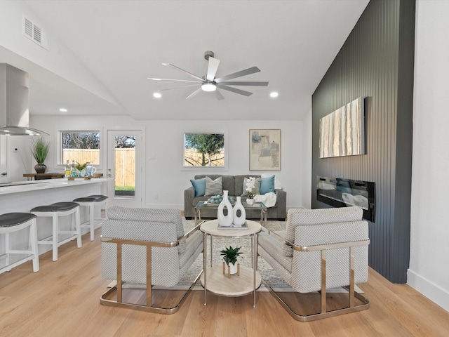 living room featuring light wood-type flooring, ceiling fan, and vaulted ceiling