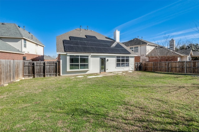 rear view of house with a lawn and solar panels