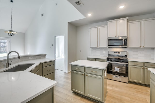 kitchen featuring decorative light fixtures, stainless steel appliances, visible vents, a sink, and a kitchen island