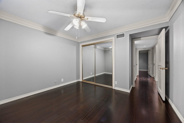 unfurnished bedroom with ceiling fan, a closet, dark wood-type flooring, and crown molding