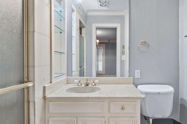 bathroom featuring toilet, vanity, a shower with door, and ornamental molding