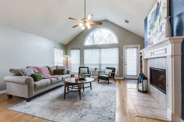 living room featuring ceiling fan, vaulted ceiling, light hardwood / wood-style flooring, and a fireplace