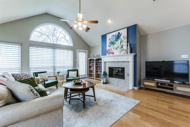 living room featuring vaulted ceiling, ceiling fan, a fireplace, and hardwood / wood-style flooring