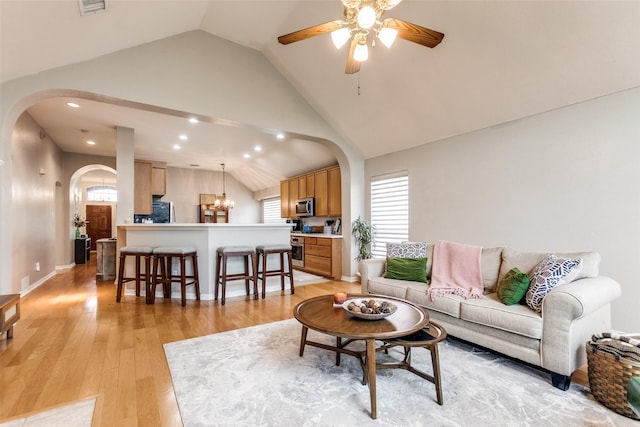 living room featuring light wood-type flooring, vaulted ceiling, and ceiling fan with notable chandelier