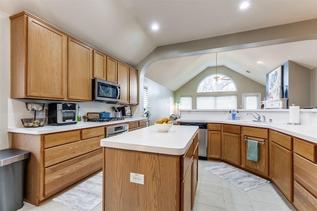 kitchen with pendant lighting, appliances with stainless steel finishes, lofted ceiling, a kitchen island, and sink