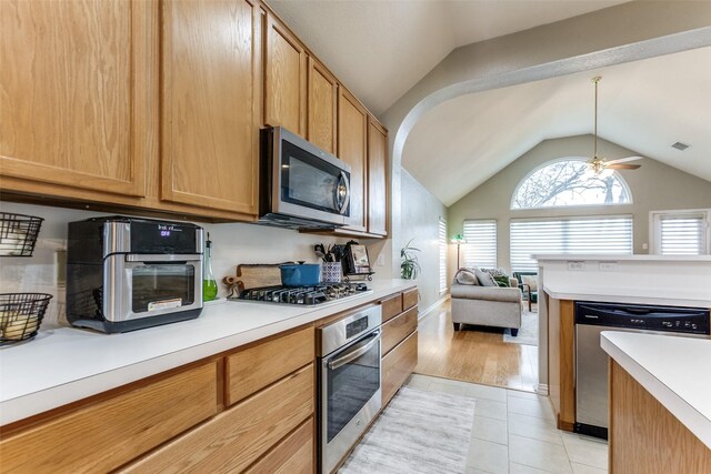 kitchen featuring vaulted ceiling, light tile patterned floors, stainless steel appliances, and ceiling fan