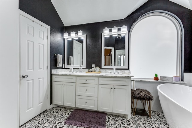 bathroom with tile patterned floors, vanity, a bathing tub, and vaulted ceiling