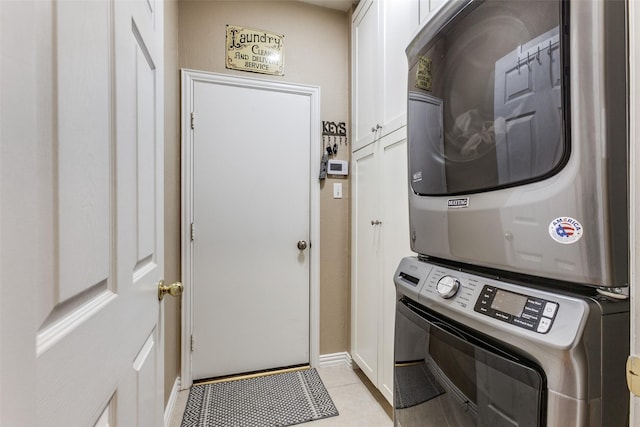 washroom featuring stacked washing maching and dryer, light tile patterned flooring, and cabinets