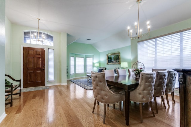 dining space with vaulted ceiling, light hardwood / wood-style floors, and a notable chandelier