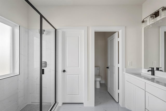 bathroom featuring toilet, vanity, and a shower with shower door