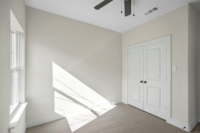 unfurnished bedroom with ceiling fan, a closet, and carpet