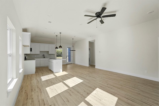 kitchen with decorative light fixtures, light hardwood / wood-style floors, white cabinetry, and a kitchen island