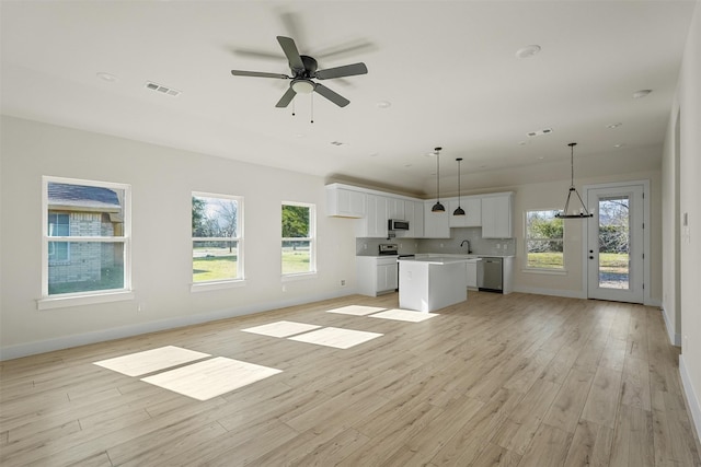 unfurnished living room with ceiling fan, a healthy amount of sunlight, sink, and light hardwood / wood-style flooring