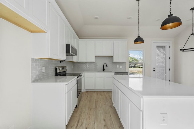 kitchen with white cabinetry, stainless steel electric range oven, decorative light fixtures, a kitchen island, and sink