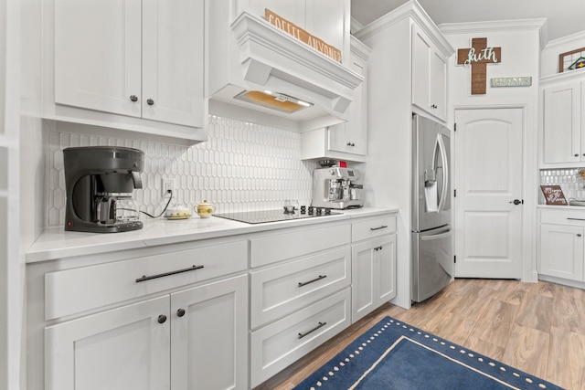 kitchen featuring white cabinetry, stainless steel refrigerator with ice dispenser, black electric stovetop, backsplash, and custom range hood