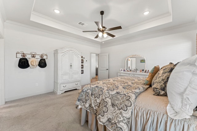 carpeted bedroom with ceiling fan, a tray ceiling, and ornamental molding