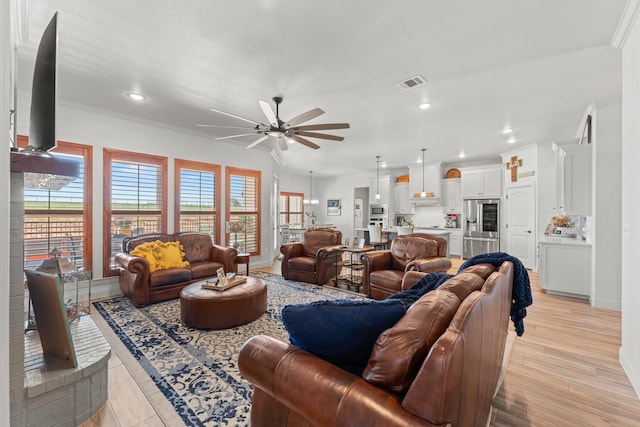 living room featuring ceiling fan, ornamental molding, and light hardwood / wood-style flooring