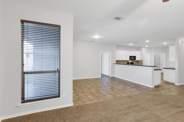 interior space featuring dark countertops, visible vents, black microwave, light carpet, and white cabinets