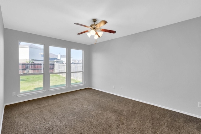 empty room with dark colored carpet, baseboards, and ceiling fan