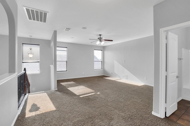 living area with arched walkways, visible vents, dark carpet, and baseboards