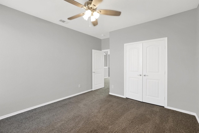 unfurnished bedroom featuring a ceiling fan, visible vents, baseboards, a closet, and dark colored carpet