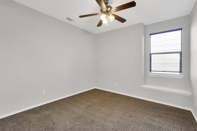 spare room with visible vents, dark carpet, baseboards, and ceiling fan