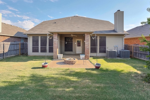 back of house featuring a patio area, a lawn, a fire pit, and a fenced backyard