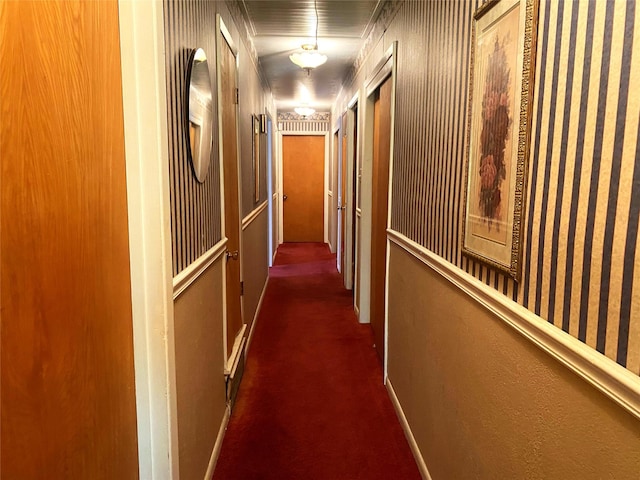 hall featuring ornamental molding and dark colored carpet