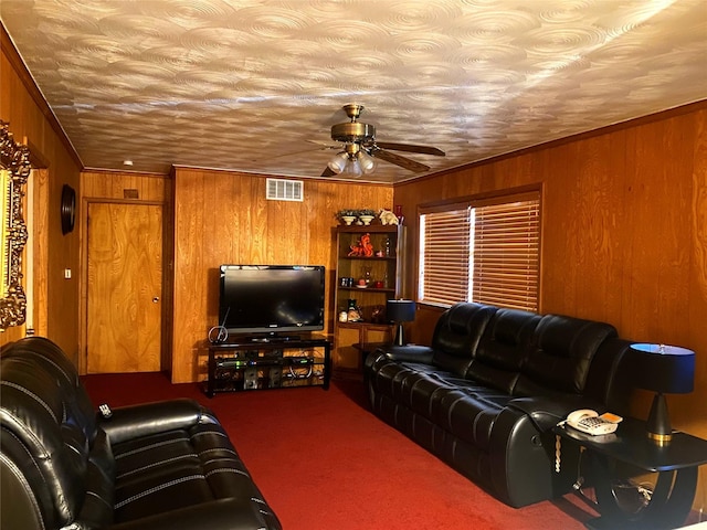 carpeted living room with ceiling fan, crown molding, wood walls, and a textured ceiling