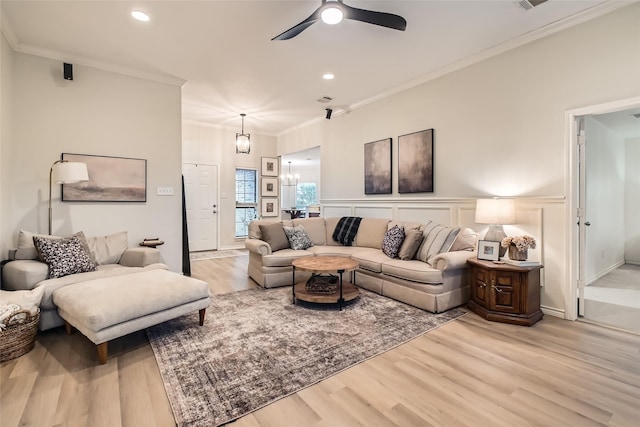 living room featuring crown molding, ceiling fan with notable chandelier, and light wood-type flooring