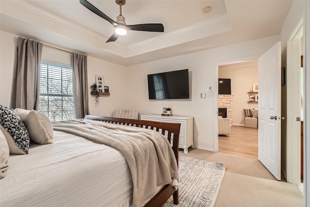 bedroom featuring light hardwood / wood-style floors, ornamental molding, a raised ceiling, and ceiling fan